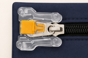 Close-up of the transparent zipper-lock base with the metal zipper pull held beneath an inserted yellow seal.