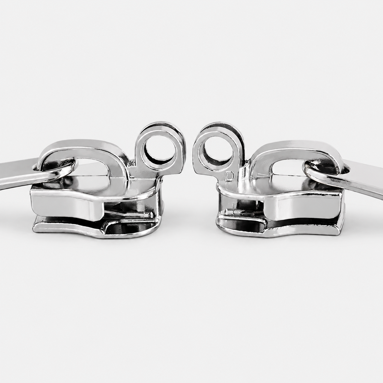 Close-up of two silver zipper sliders with lock holes